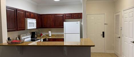 A kitchen with wooden cabinets, a white refrigerator, a microwave, and a sink.