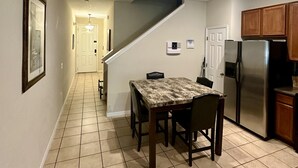 A kitchen with a dining table, chairs, a refrigerator, and wooden cabinets. - Grand Panoramic 3BR Townhouse Near Disney (Kissimmee)