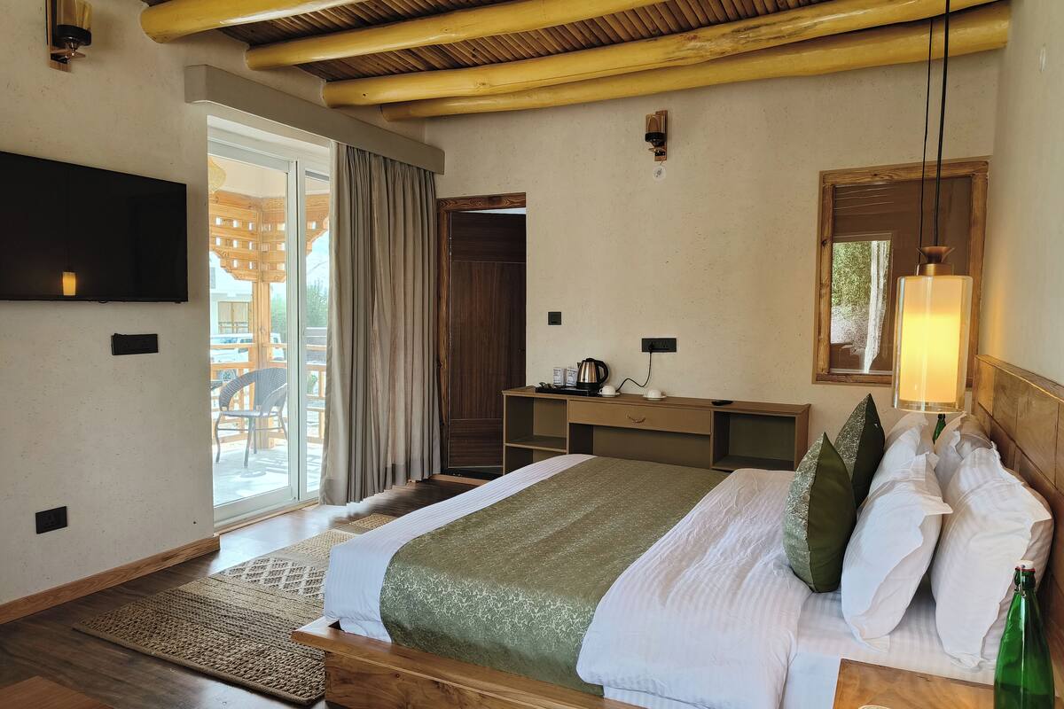 A hotel room with a bed, a desk, a TV, and a window with curtains.