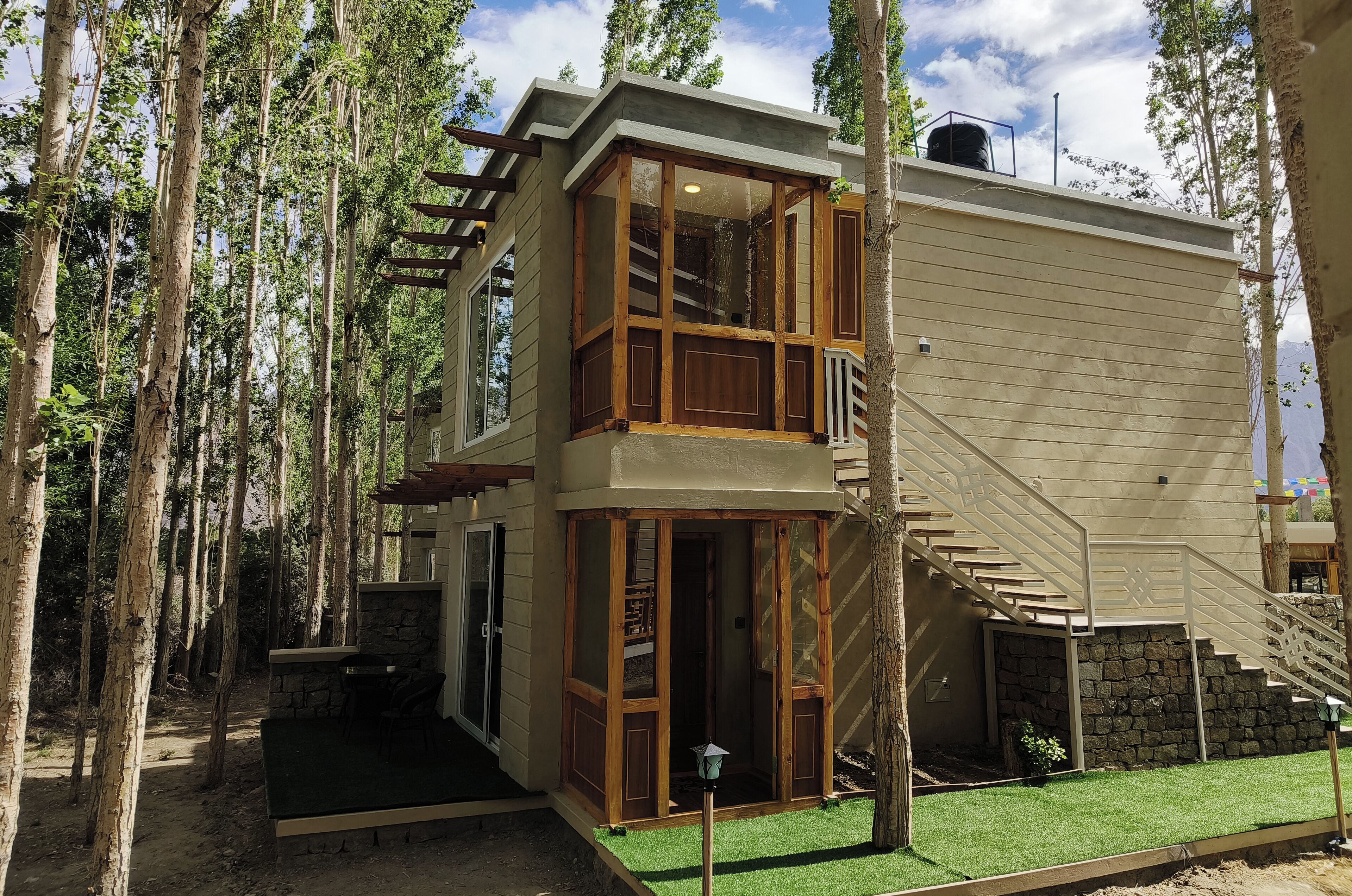 A two-story building with a wooden balcony, a stone wall, and a staircase leading to the upper level.