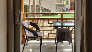 A wooden pergola with a hanging light fixture, two wicker chairs, and a table outside a building. - The Unalome Resort (Leh)