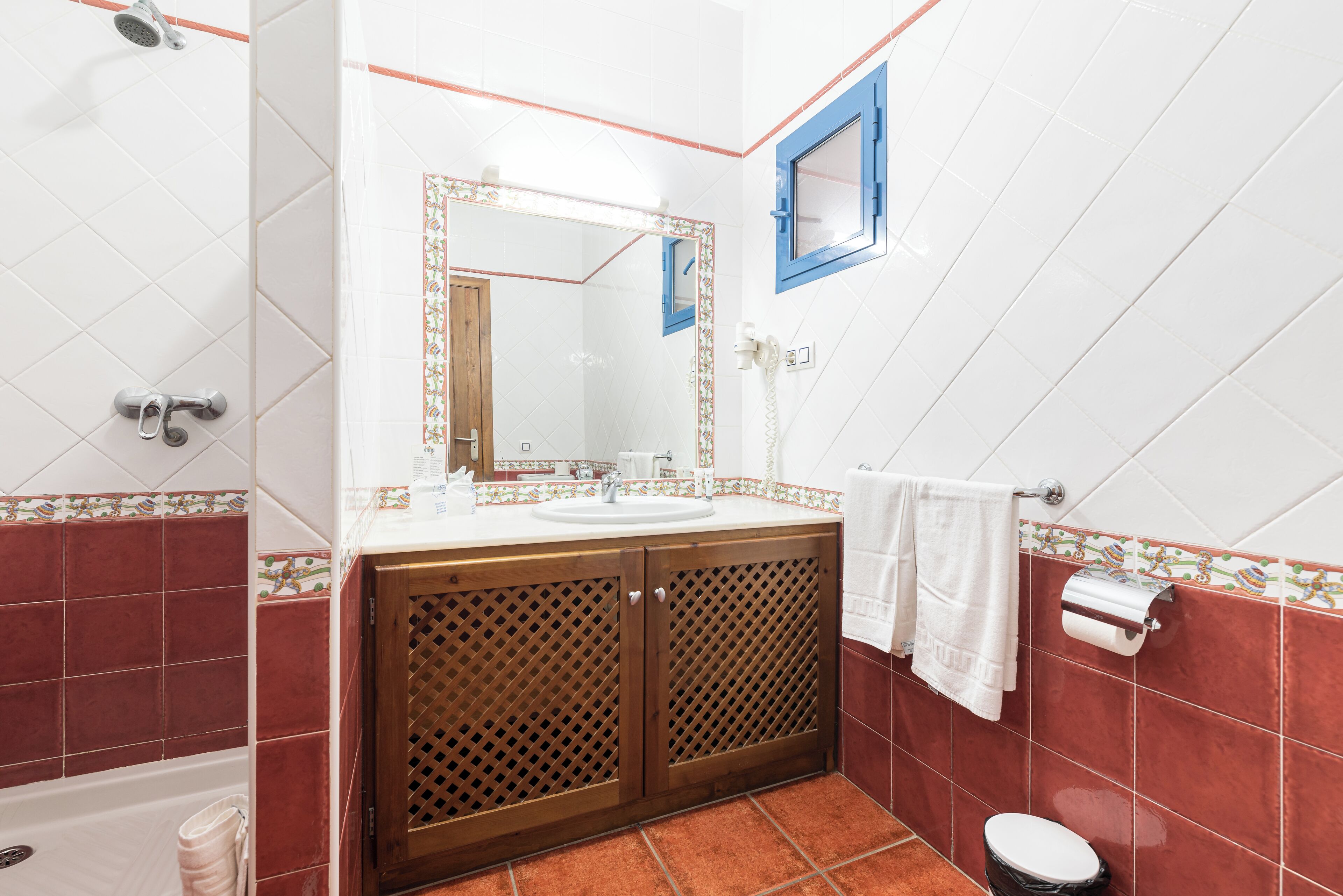A bathroom with a sink, mirror, shower, and toilet.