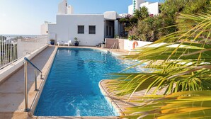 A swimming pool with a white building in the background, a metal railing, and some greenery. - El Dorado San Jose (San José)