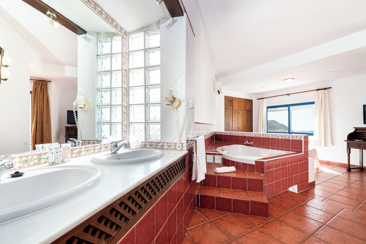 Une salle de bain avec deux lavabos, une baignoire et un grand miroir.