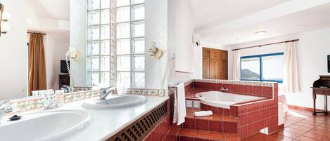 Un baño con dos lavamanos, una bañera y un espejo grande.