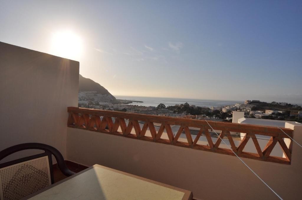 A balcony with a view of the sea and a cityscape.