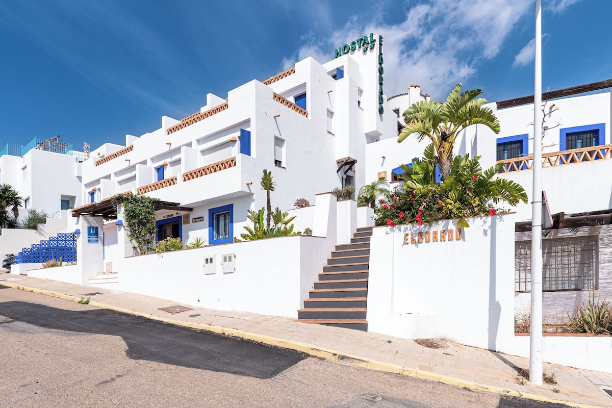 Un bâtiment blanc agrémenté de touches de bleu et portant une enseigne indiquant « Hostal ».