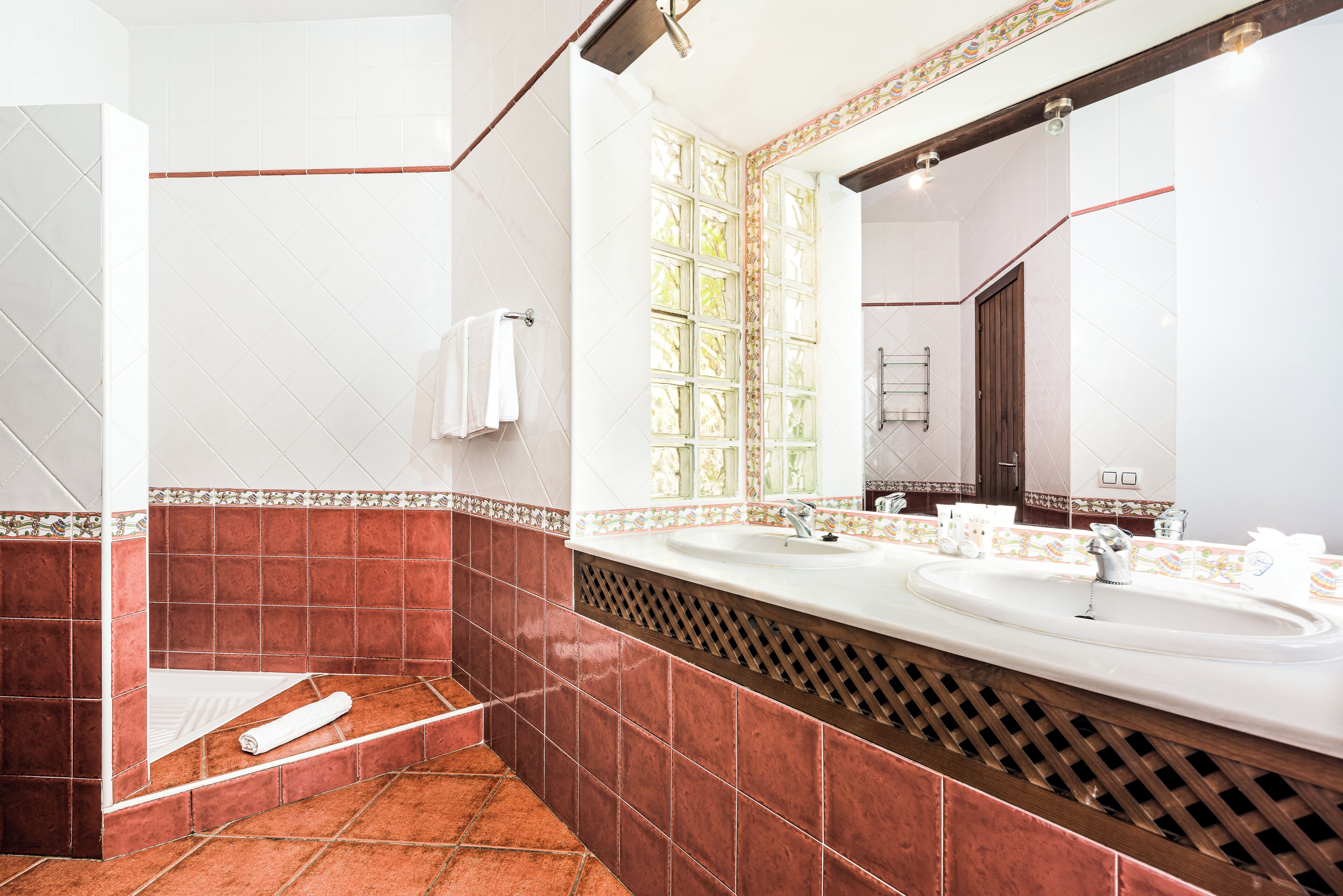 Ein Badezimmer mit zwei Waschbecken, einer Dusche und einem großen Spiegel.
