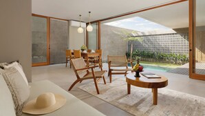 A modern living room with a large glass door leading to a pool area, wooden furniture, and a view of the outdoors. - Pulang Villas Private Pool Pererenan (Canggu)