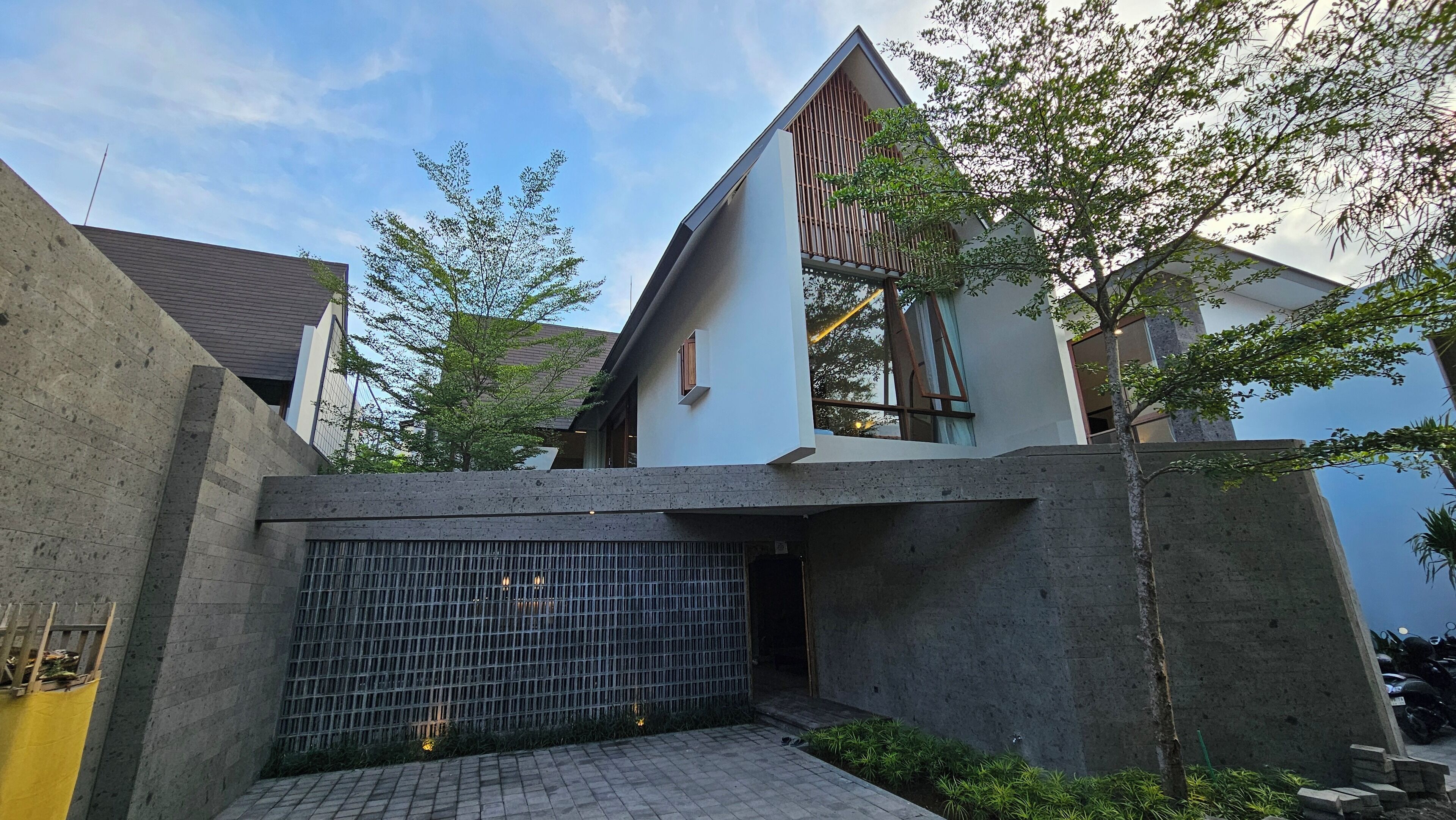 A modern building with a concrete facade, a metal gate, and a small garden area with plants.