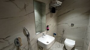Et badeværelse med marmorgulv, vask, toilet, brusebad og spejl.