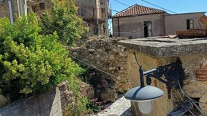 Un étroit sentier de pierre mène à un bâtiment surmonté d’un toit en tuiles.