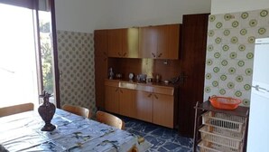 Un coin repas avec une table dressée pour deux personnes, une cuisine dotée de meubles en bois et d’un plan de travail carrelé.