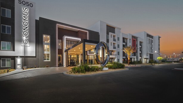 Un hôtel moderne doté d’une entrée imposante, d’une grande sculpture circulaire et d’une façade bien éclairée.