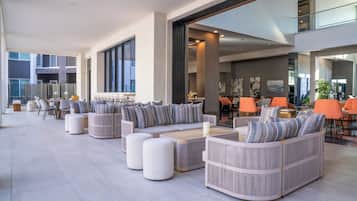 A spacious outdoor seating area with modern furniture, large windows, and a view of the cityscape.