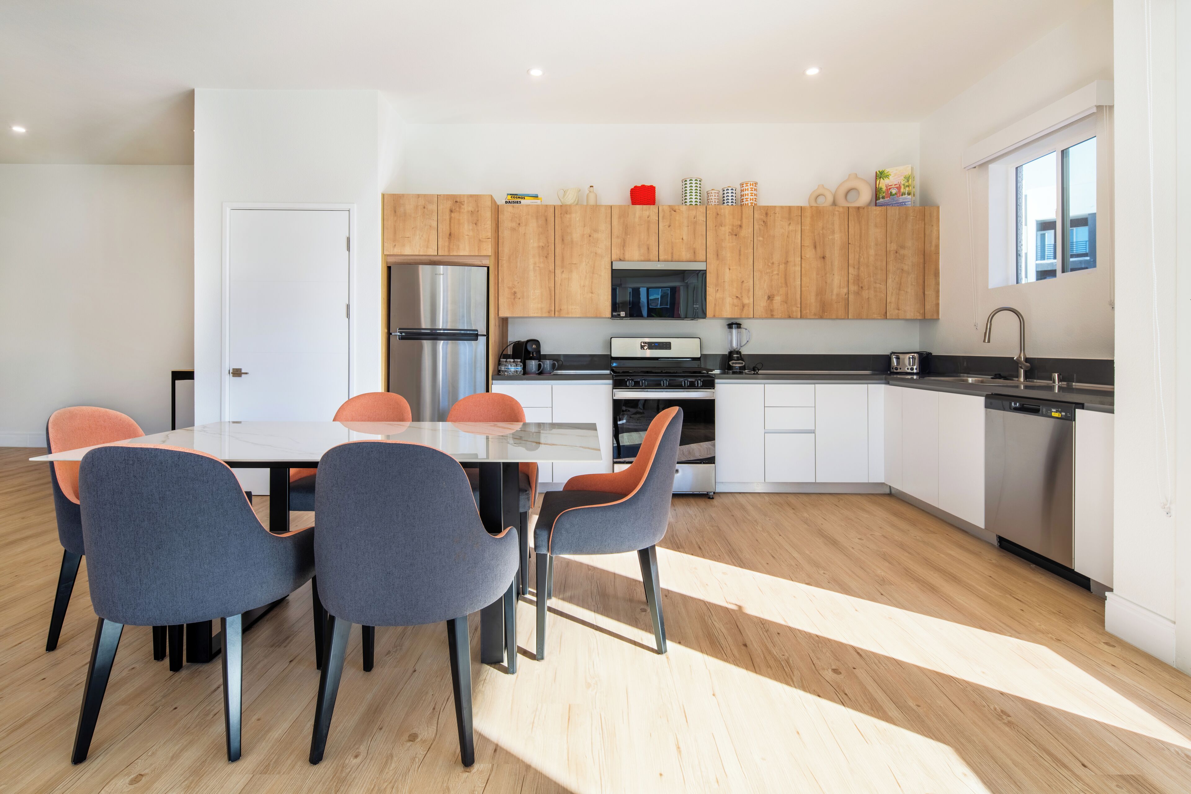 A modern kitchen with a central island, white cabinets, and a stainless steel refrigerator.