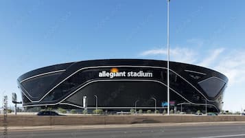 En modern arena med ett böjt tak och namnet ”Allegiant Stadium” tydligt synligt.
