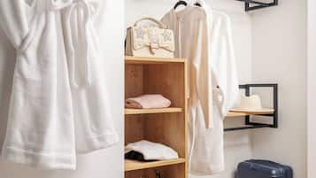 A neatly organized wardrobe with hanging robes, folded towels, and a handbag.