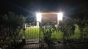 Ein verschlossenes Tor zu einem Anwesen bei Nacht, mit einem gut beleuchteten Eingangsbereich.
