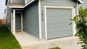 Ein zweistöckiges Wohnhaus mit Garage, Eingangstür und kleiner Veranda.
