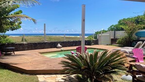 Ein Garten mit Swimmingpool, Holzterrasse und Liegestühlen.