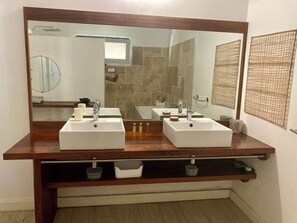 Une salle de bain avec deux lavabos, un grand miroir et un meuble-lavabo en bois.