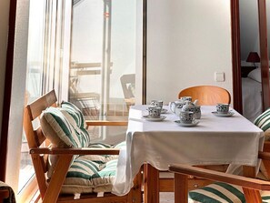 A dining area with a table set for tea, surrounded by striped cushioned chairs.