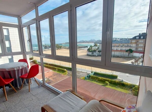 Una habitación con amplios ventanales que dan a una playa y un estacionamiento.