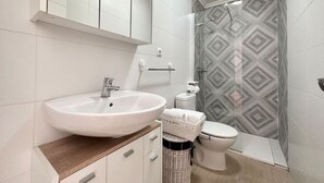A modern bathroom with a white sink, a toilet, and a shower. - El Patuco - 30013 (Somo)