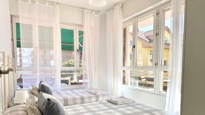 A bedroom with two beds, a window with curtains, and a view of buildings outside. - El Patuco - 30013 (Somo)