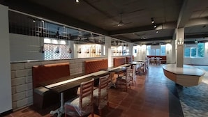 Un restaurante amplio con techos altos, conductos expuestos y una variedad de opciones de asientos, incluyendo cabinas y mesas.