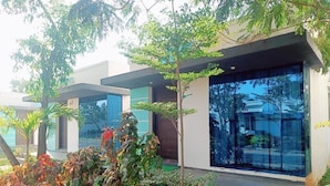Un edificio moderno con amplios ventanales y un jardín con diversas plantas.