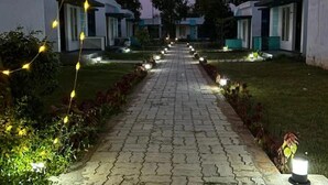 Un camino conduce a una hilera de edificios modernos de una sola planta, con un diseño exterior uniforme, rodeados de céspedes bien cuidados e iluminación decorativa.