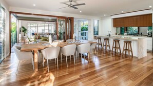 A spacious kitchen with a wooden island, bar stools, and a dining area with chairs. - Headlands Hideaway, Moffat Beach Dog Friendly Home (Caloundra Region)