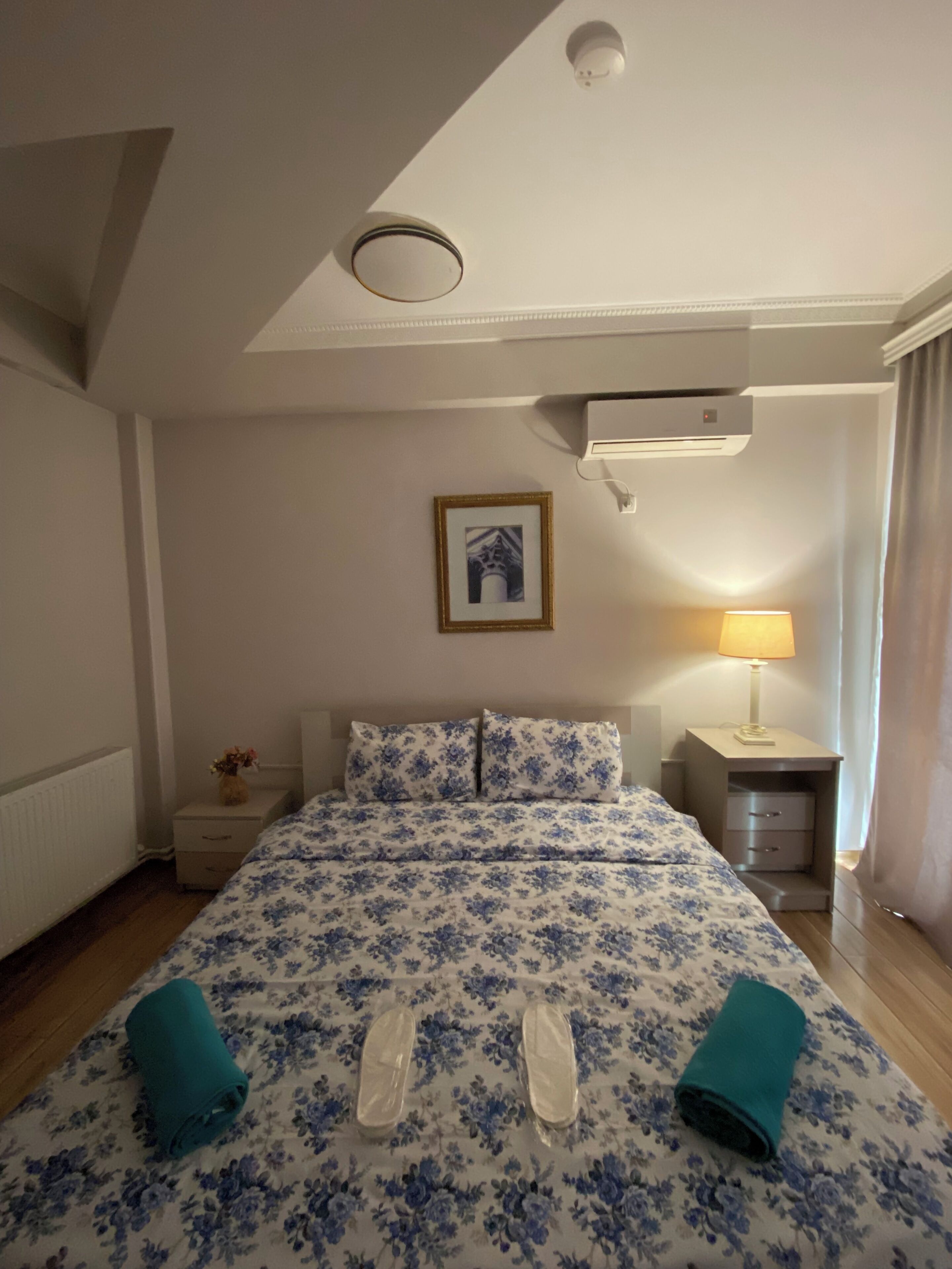 Ein Hotelzimmer mit einem Bett, einem Nachttisch, einer Lampe und einem Bild an der Wand.