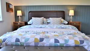 A bed with a tufted headboard, a quilted bedspread, two bedside tables with lamps, and a nightstand with a lamp.