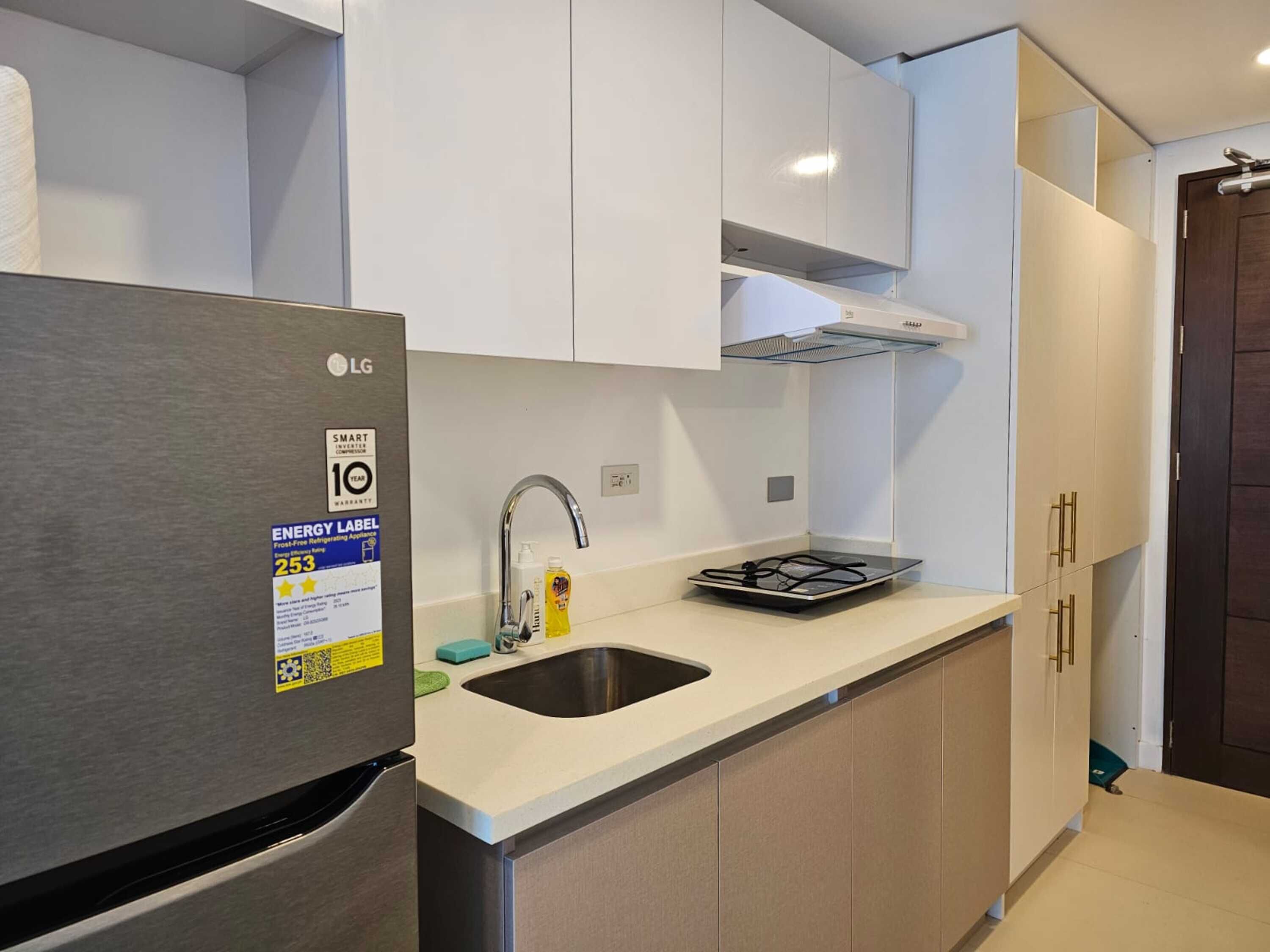 Una cocina moderna con armarios blancos, un refrigerador de acero inoxidable y una estufa integrada.