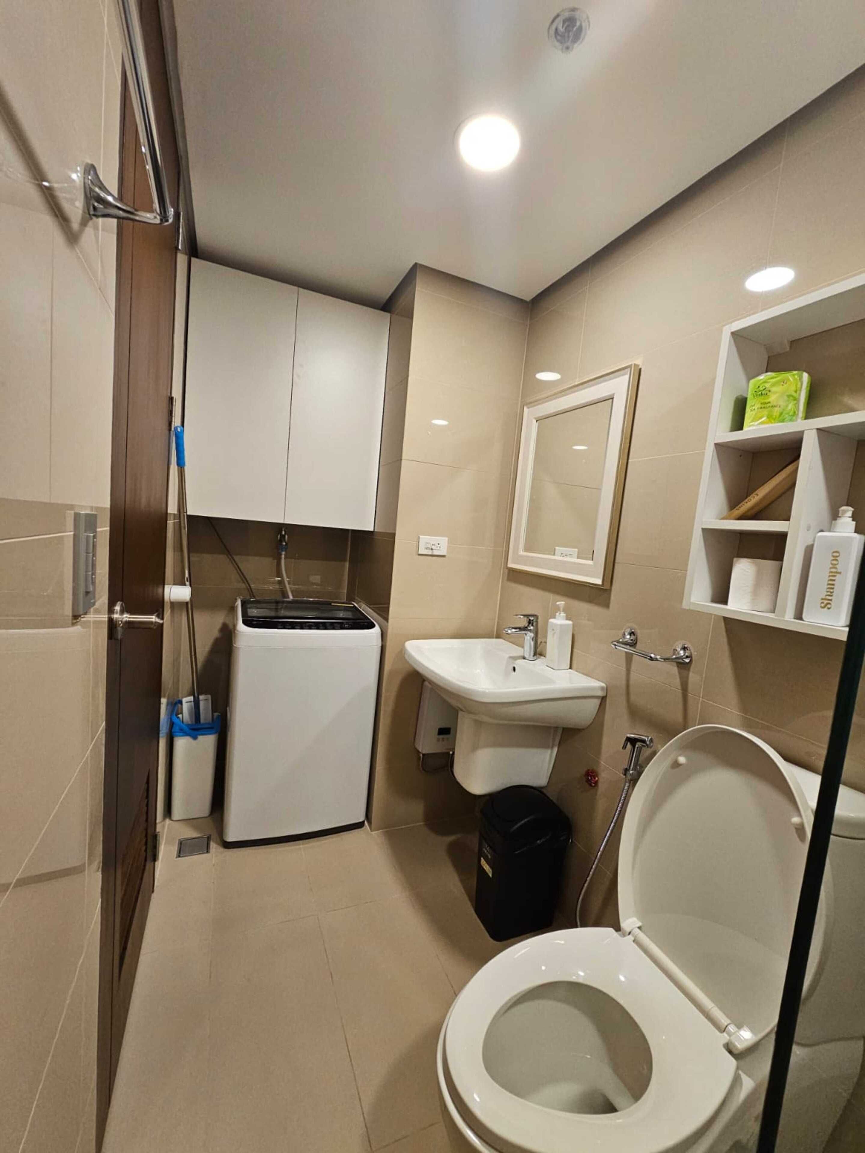 A compact bathroom with a toilet, sink, and a small washing machine.