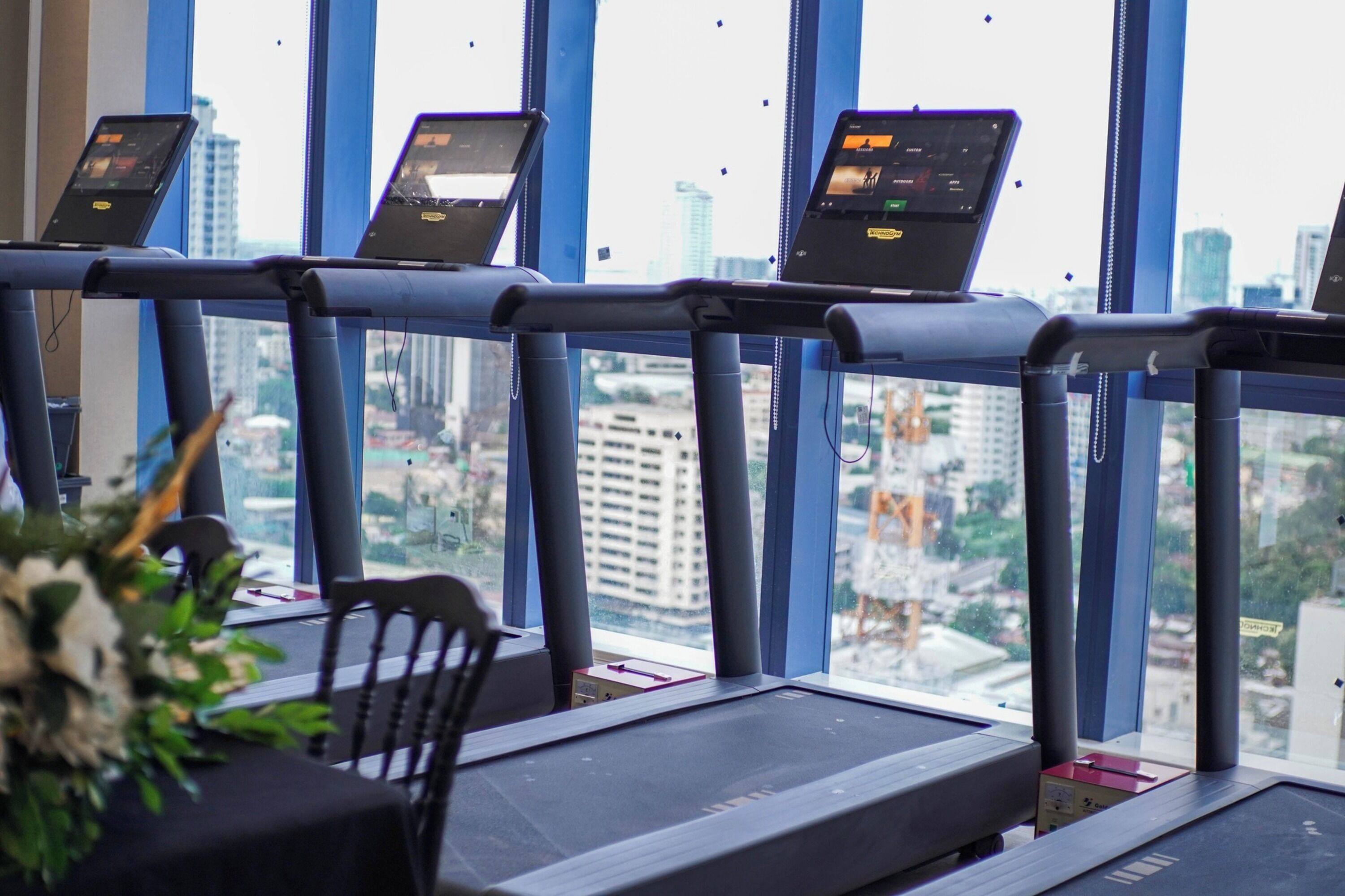 A treadmill with a city view through large windows.