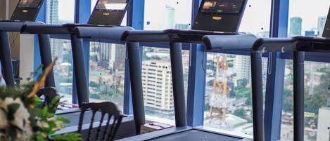 A treadmill with a city view through large windows.