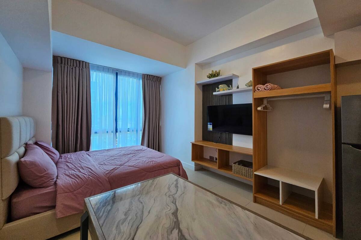 Una habitación de hotel moderna con cama, sofá, televisor y armario.