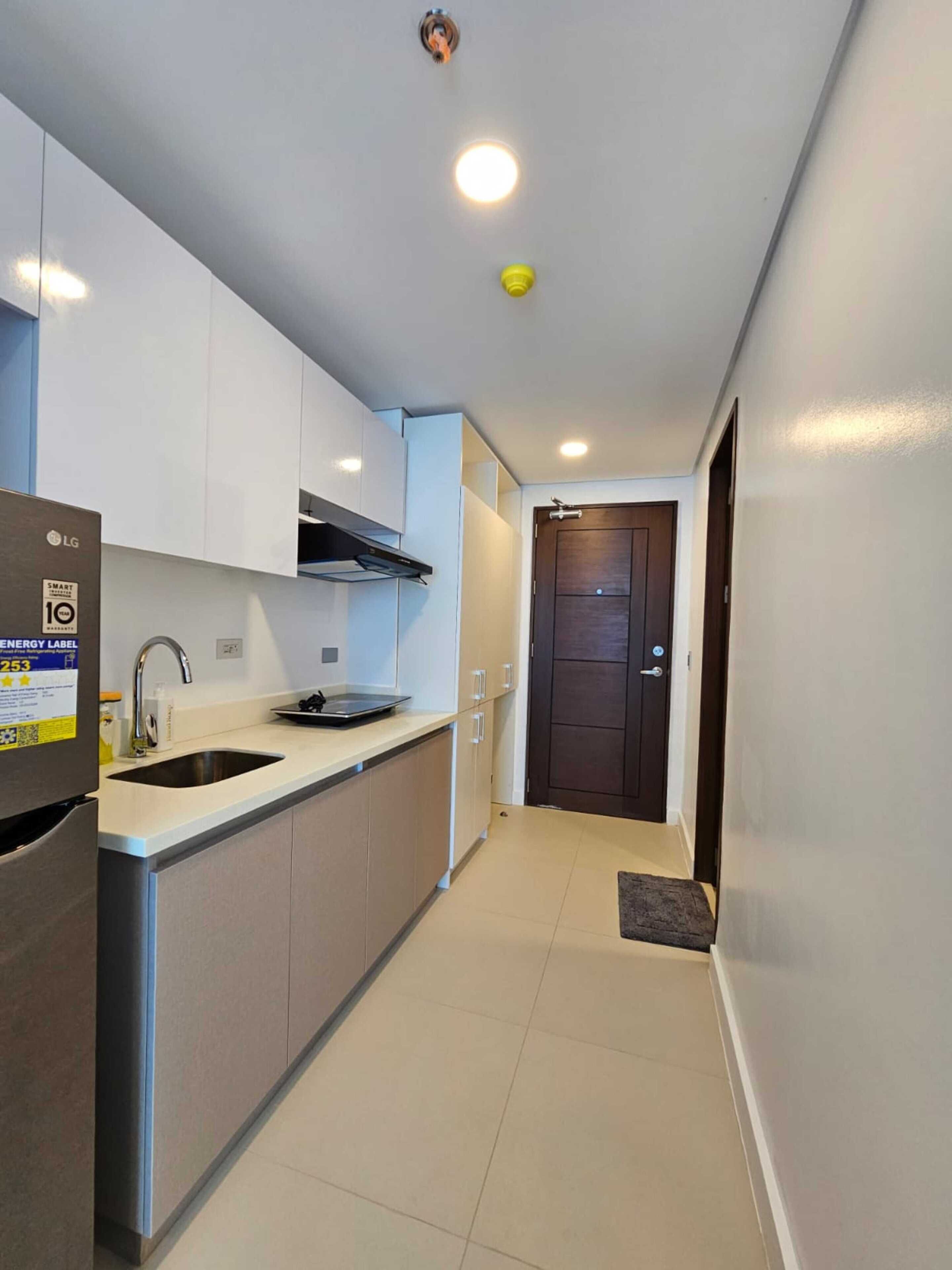 A compact kitchen with white cabinets, a stainless steel sink, and a black stove.