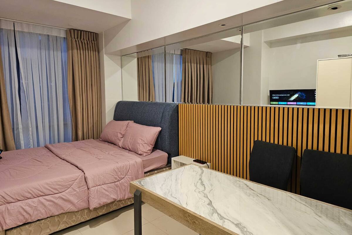 Una habitación de hotel moderna con cama, escritorio y televisión.