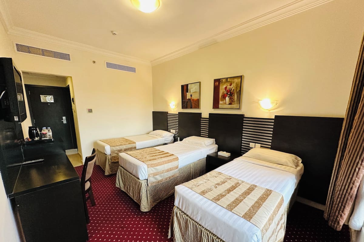 Habitación de hotel con dos camas, un escritorio, una cafetera y un cuadro en la pared.