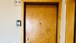 A wooden door with a peephole and a doorbell, a handrail, and a small sign indicating the apartment number. - Triplex Two-Bedroom Ap with amazing View (Oporto)