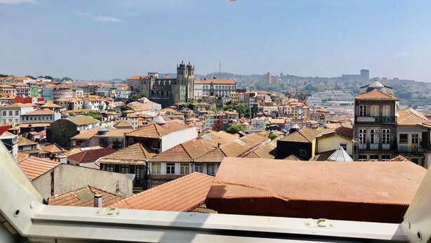 A cityscape viewed from a high vantage point, featuring a prominent church with a bell tower, surrounded by densely packed buildings with red-tiled roofs. - Triplex Two-Bedroom Ap with amazing View (Oporto)