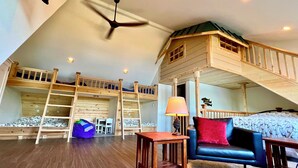 A loft bedroom with bunk beds, a playhouse, a desk, and a chair.