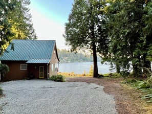 A cabin with a metal roof, a gravel driveway, and a lake view. - Serenity Shores: Lakefront Vacation Home with Indoor Playhouse! (Eatonville)