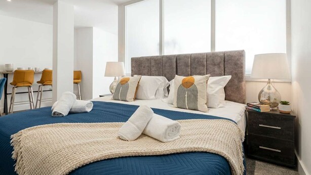 A hotel room with a large bed, a desk, chairs, and a window.