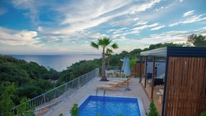 A rooftop pool with a view of the sea, surrounded by greenery and wooden structures. - Lastura Mobile Homes (Novalja)
